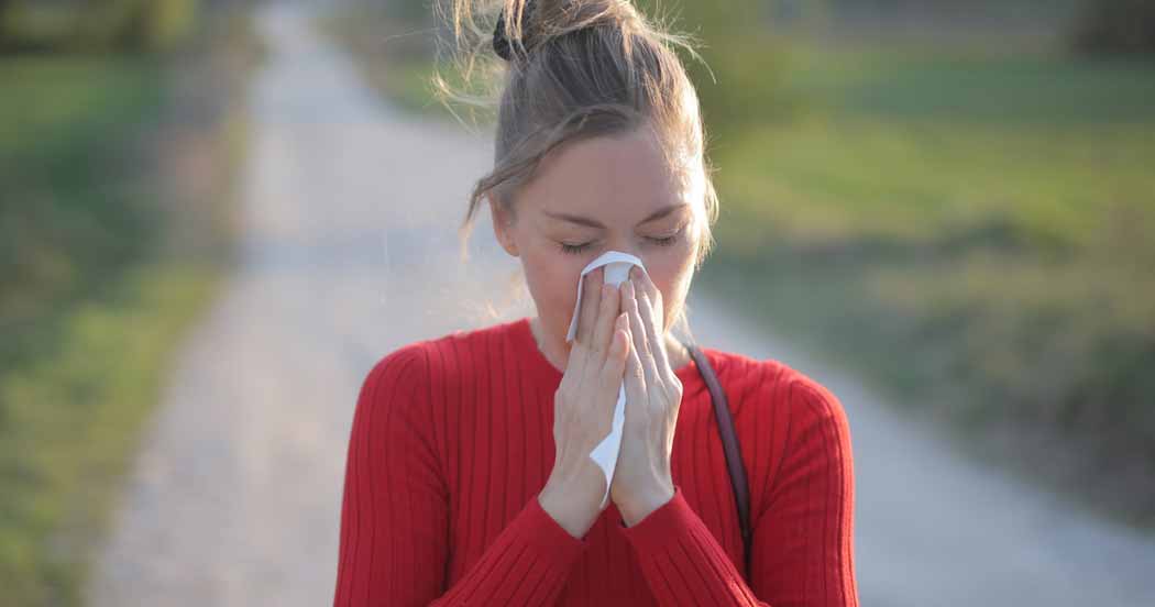 woman walking on path with tissue on her nose